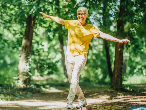 Ein lächelnder älterer Erwachsener mit kurzen grauen Haaren, in gelbem Hemd und heller Hose, balanciert auf Holzstümpfen in einem sonnigen Wald - er strahlt Vitalität aus, die die natürlichen Vorteile von BIO Pleurotus Extrakt unterstreicht.