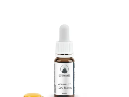 Ein kleines braunes Glasfläschchen mit der Aufschrift Vitamin D 1000 flüssig und einem weißen Tropfverschluss, abgebildet neben einem Tropfen gelber Flüssigkeit und einer klaren Kugel, auf weißem Hintergrund.