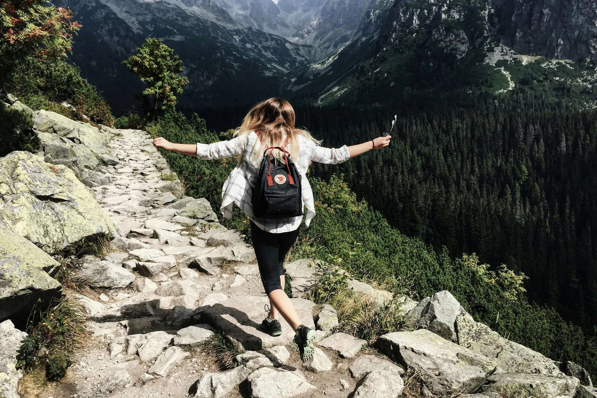 Frau wandert auf steinigem Bergpfad – Symbol für natürliche Bewegung zur Knochengesundheit
